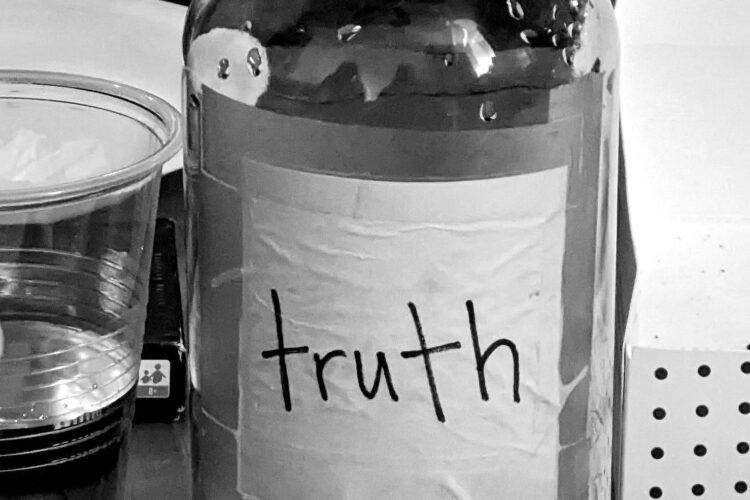 A bottle of water with the label truth, in black and white set on a table